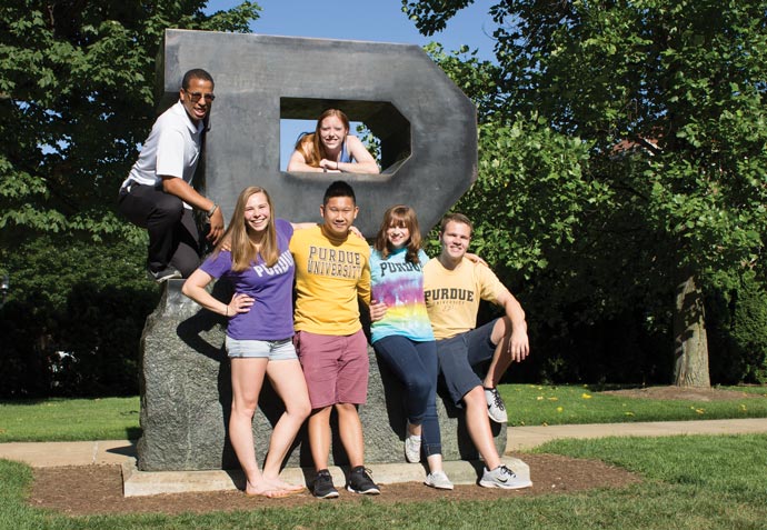 students posing with the block P statue