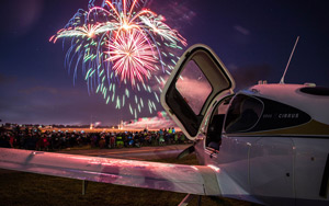 A photo of fireworks in the background and Purdue plane in the foreground