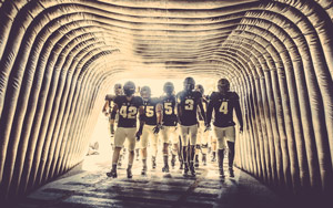 A photo of the football team backlit and entering a tunnel