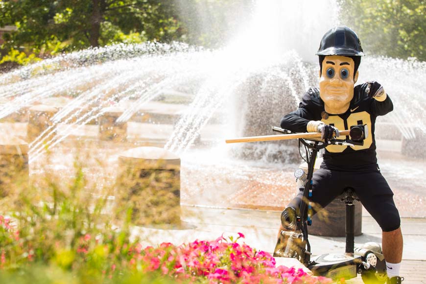 Purdue Pete by fountain pointing to viewer