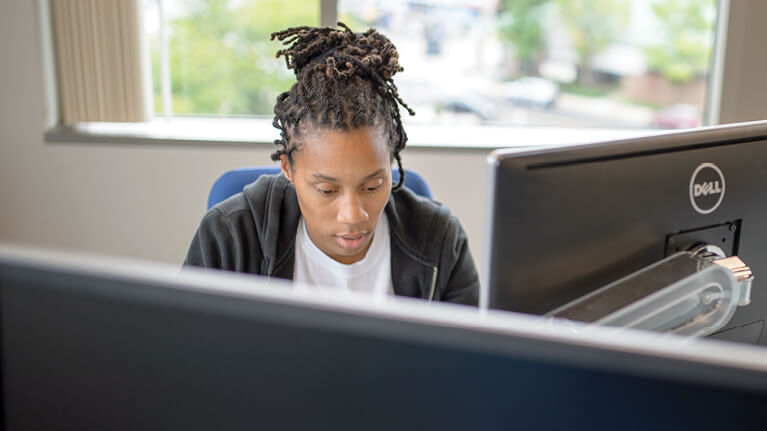 A student working behind two computer monitors