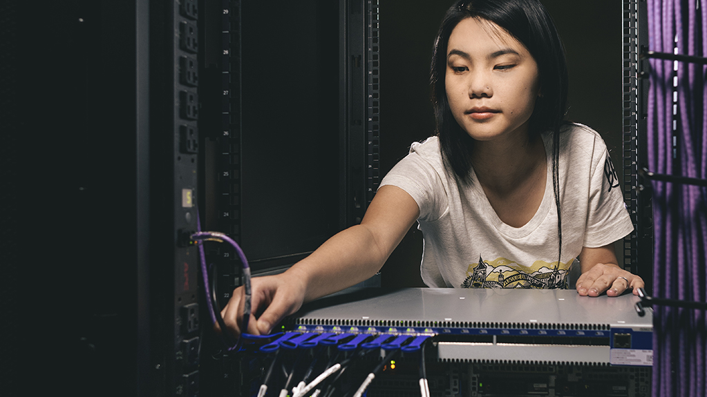 Computer science student adjust cords in a server