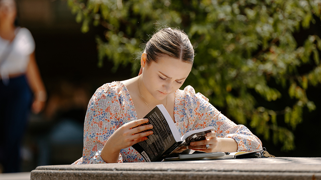 A student reads a book outside
