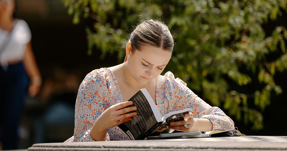 A student reads a book outside