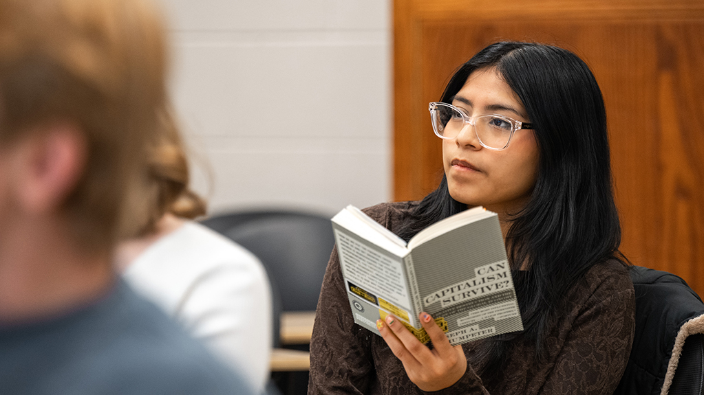A student looks up from reading a book about capitalism