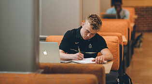 Student writing at desk.