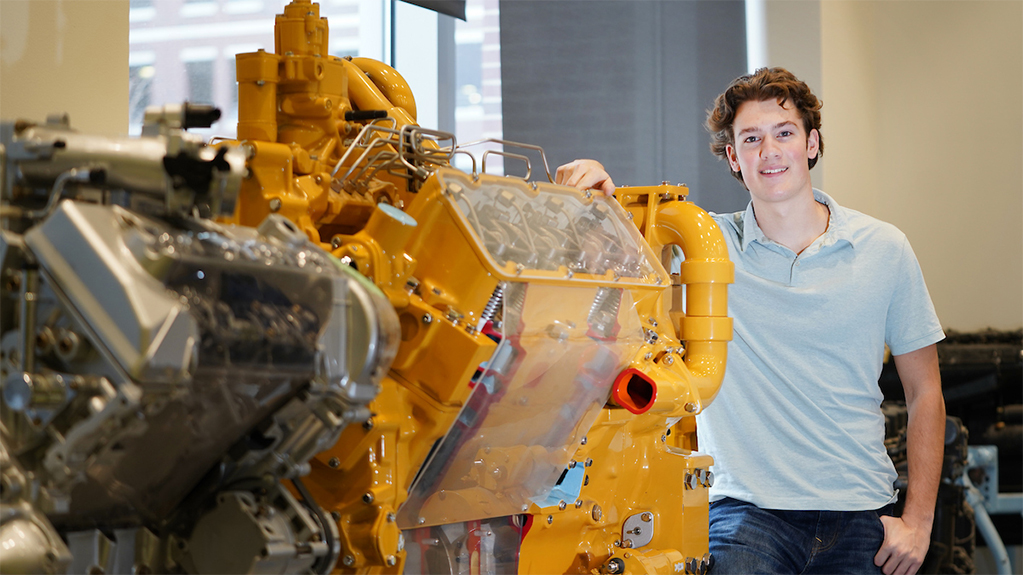 Student standing next to large engine