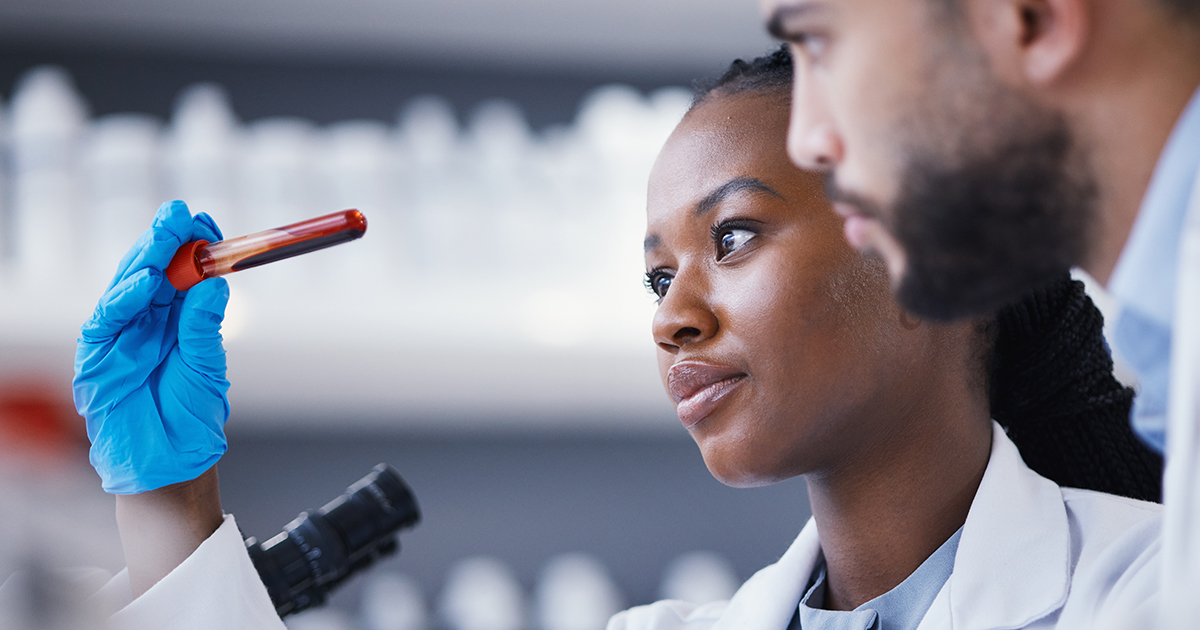 Colleagues look at a vial sample together in a science lab