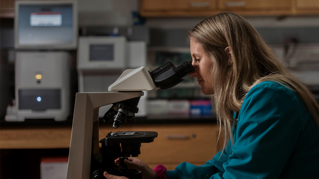 Female student looking through microscope