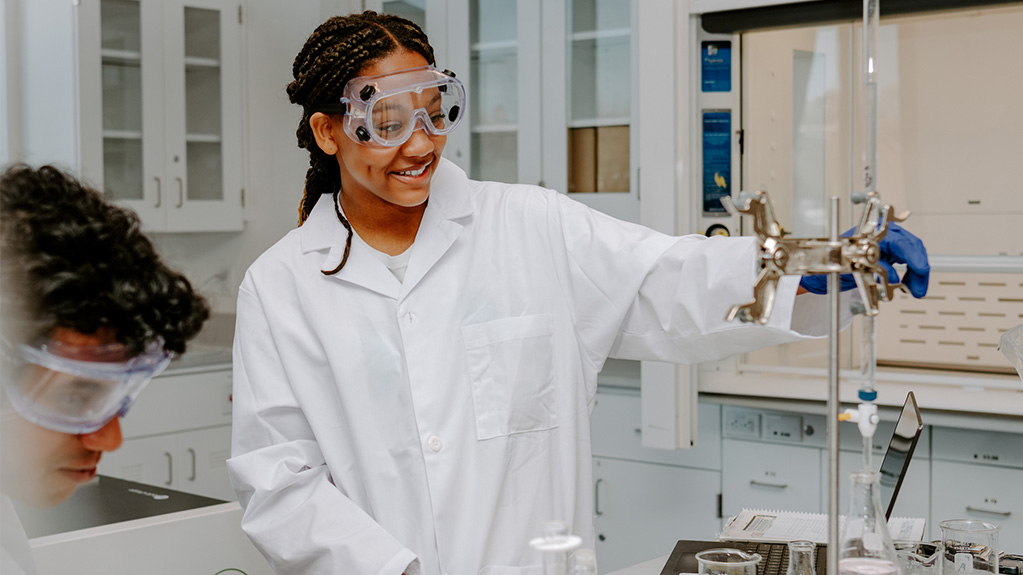 student smiling using chemistry lab equipment