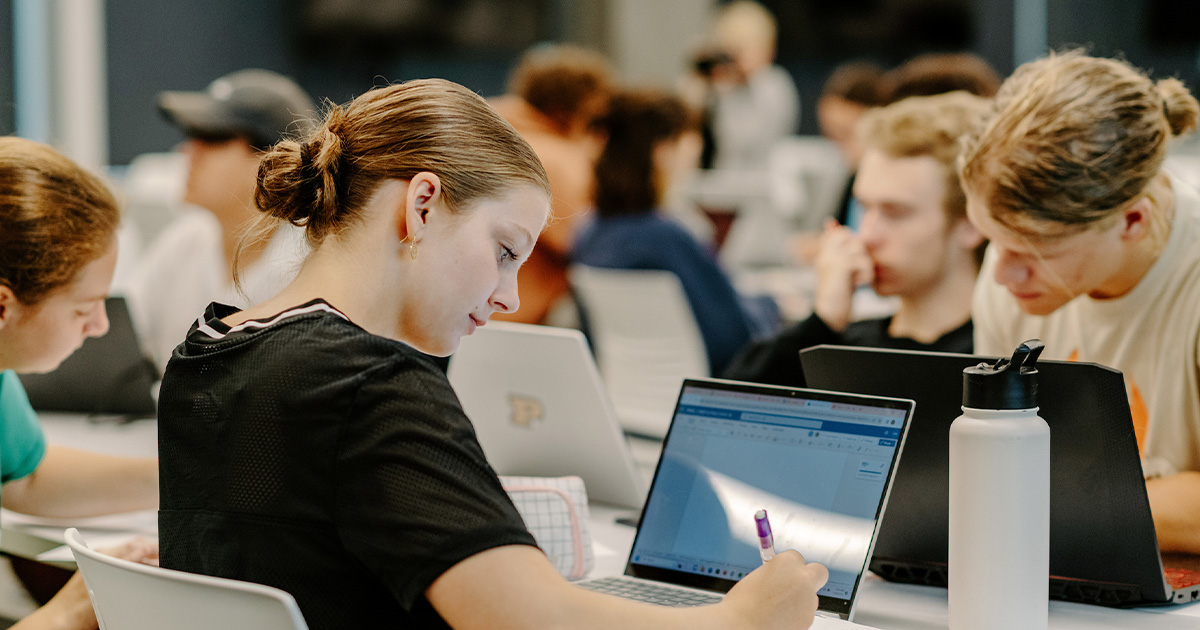 Girl studying in room full of students