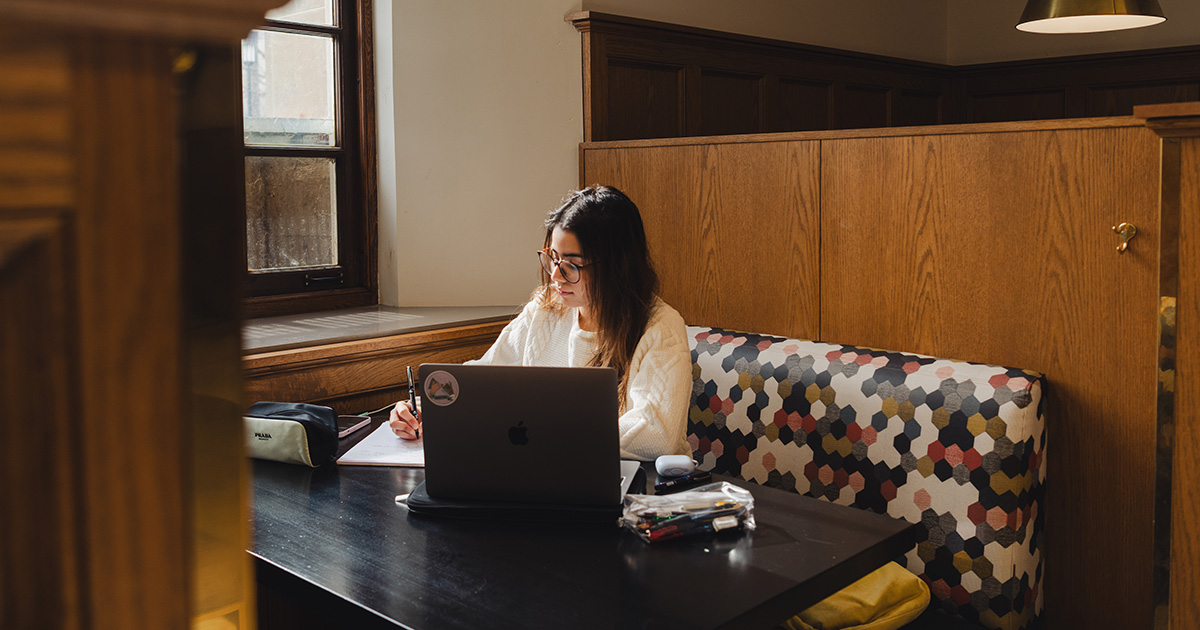 Girl studying at table with laptop