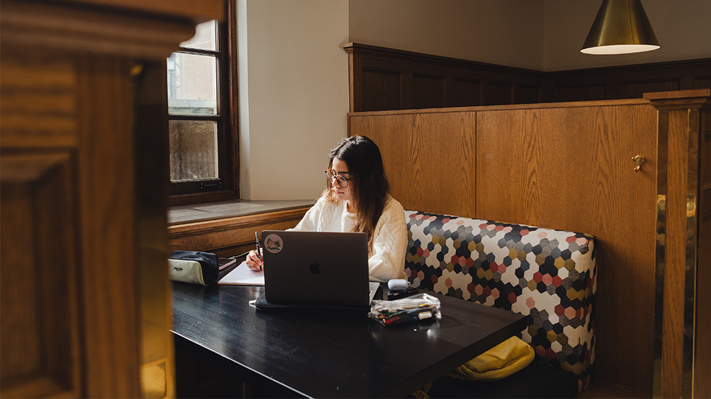 Girl studying at table with laptop