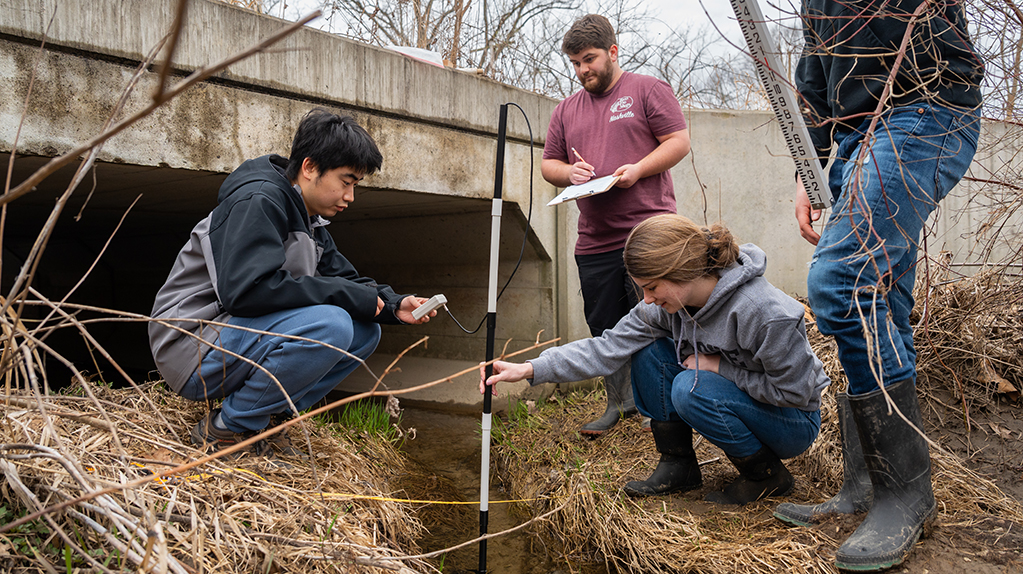 Group of students taking water samples in creek