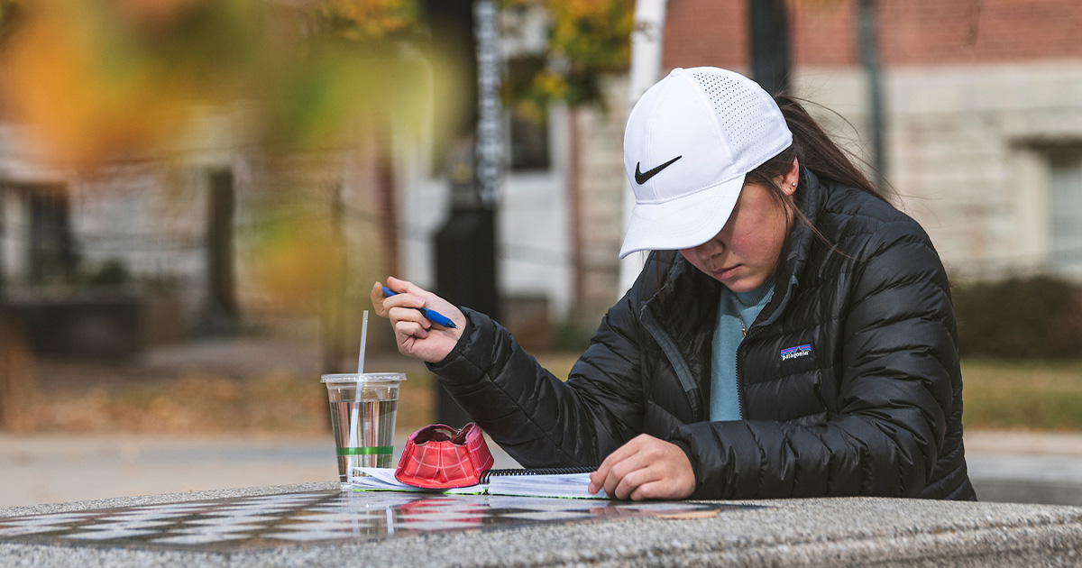 girl studying at table outside.