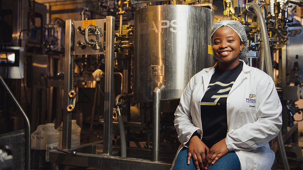 A students sits beside machinery in the food science lab