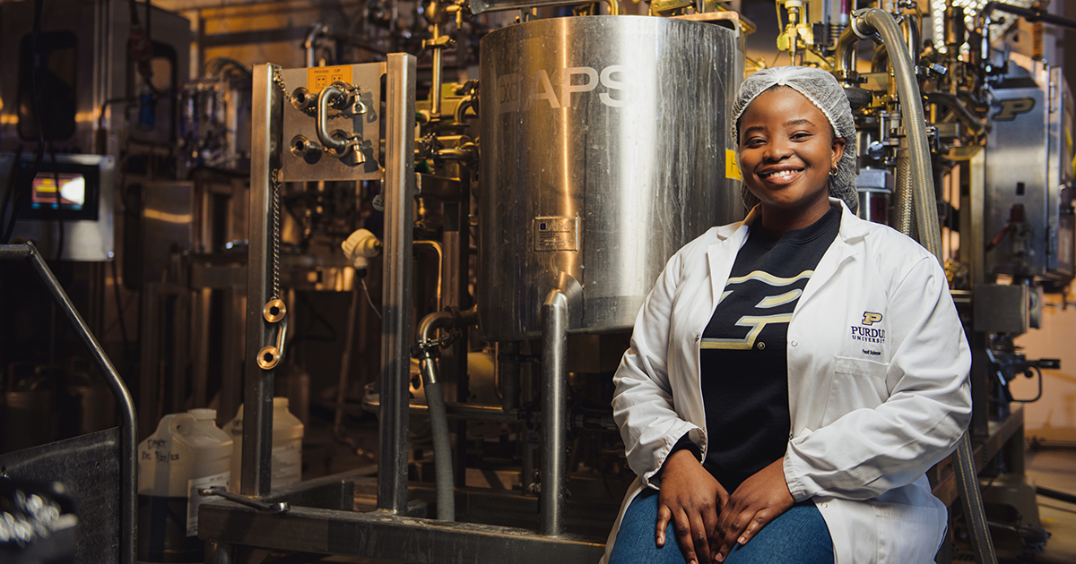 A students sits beside machinery in the food science lab
