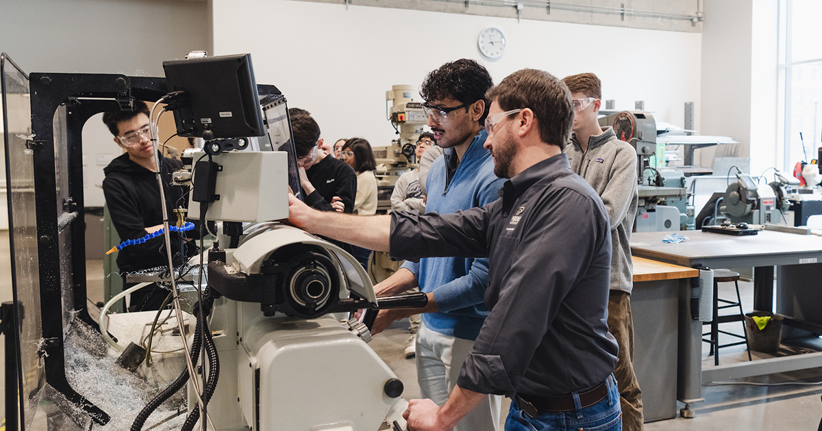 instructor talking with student in front of machinery