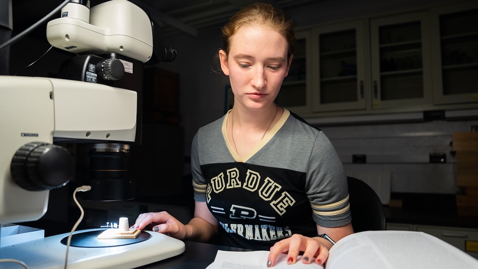 Student sitting behind a microscope in a lab