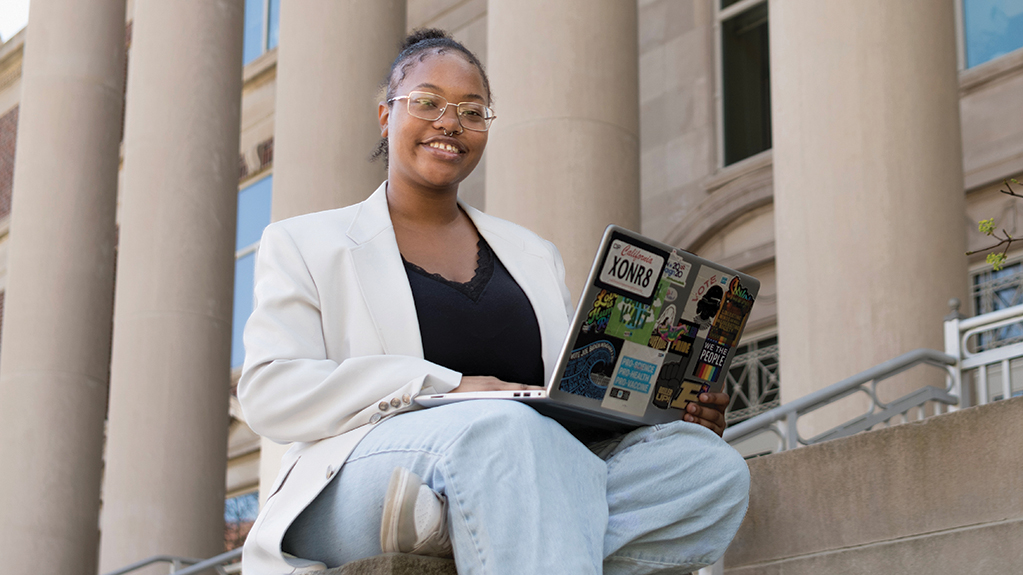 A student works on her laptop as she sits outside of a courthouse