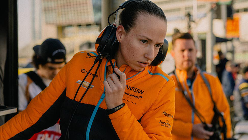 Lizzie Todd intently looks on as she listens in her headset at the race track