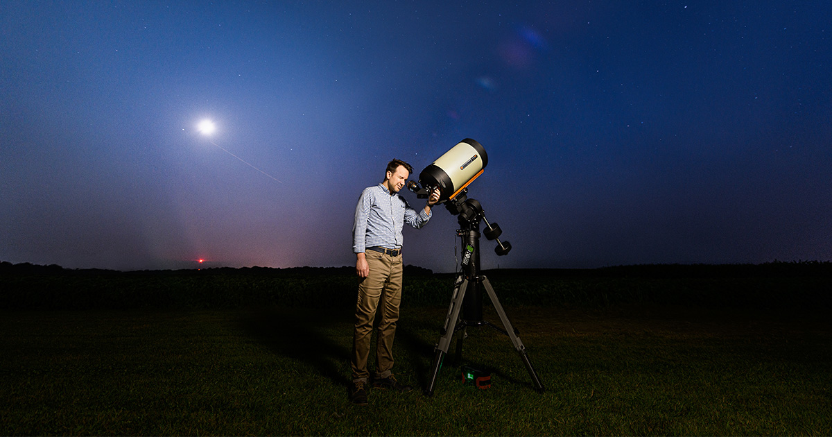 person looking in a telescope at night