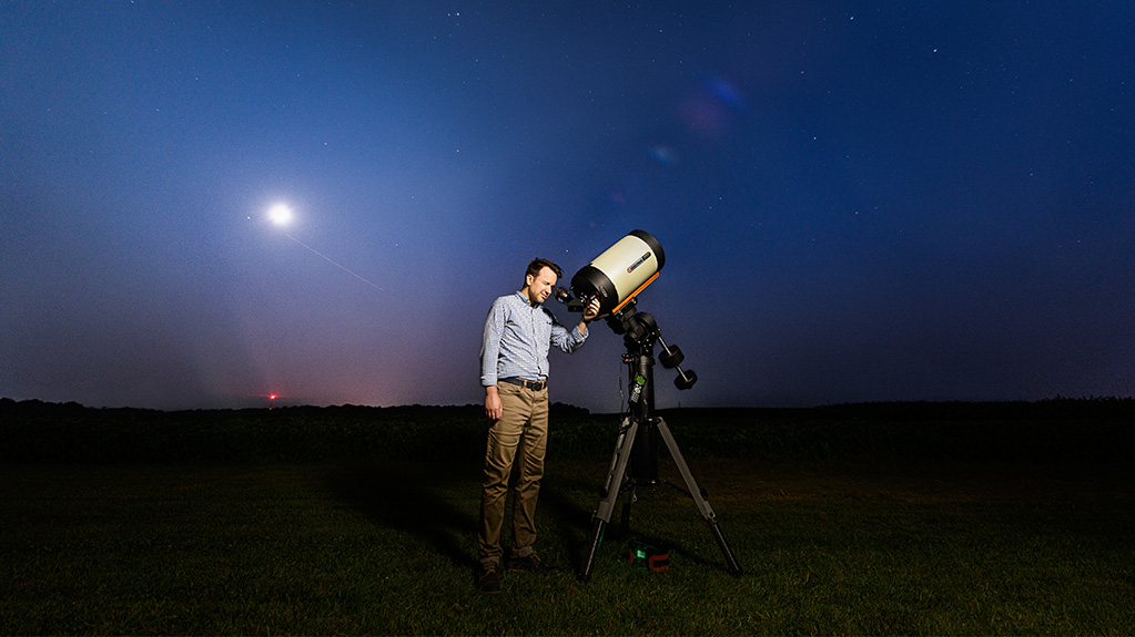 person looking in a telescope at night