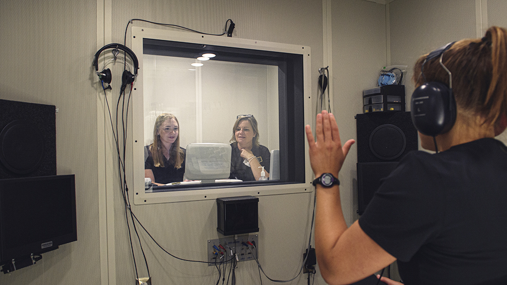 A woman takes a hearing test in a sound proof room