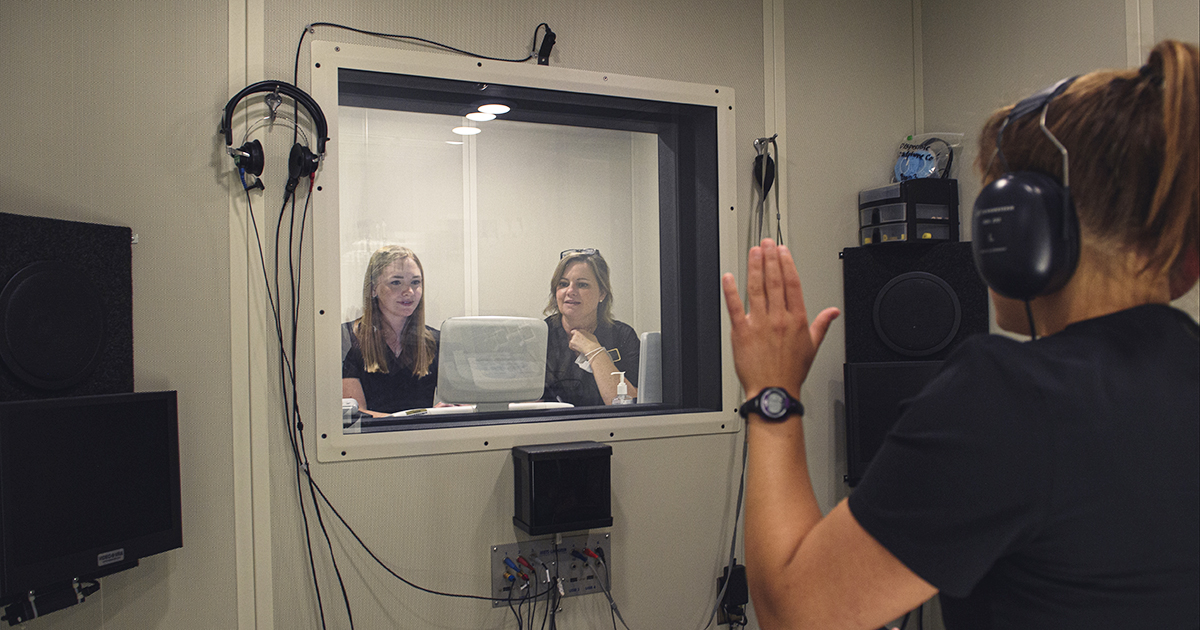 A woman takes a hearing test in a sound proof room
