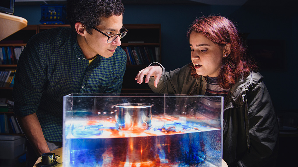 two students looking over a box of colored liquid