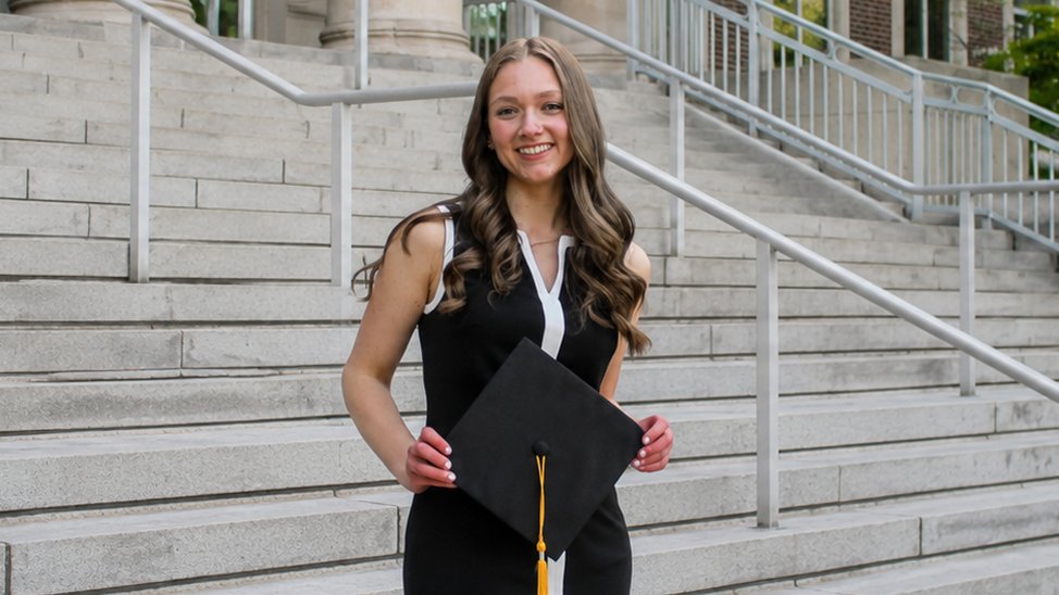 Sophia Cavanagh posing with her graduation stole and cap on Hovde Hall steps