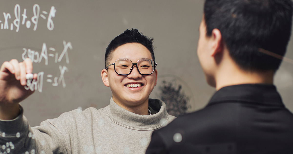 Student smiling while solving a math problem