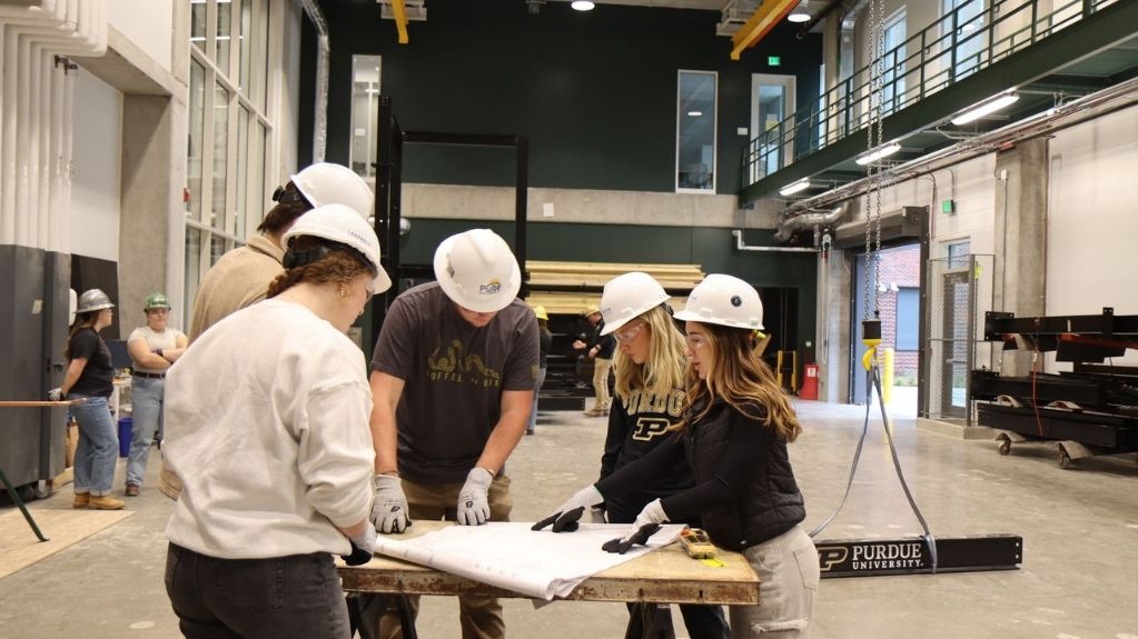Students wearing hard hats reviewing construction plans.