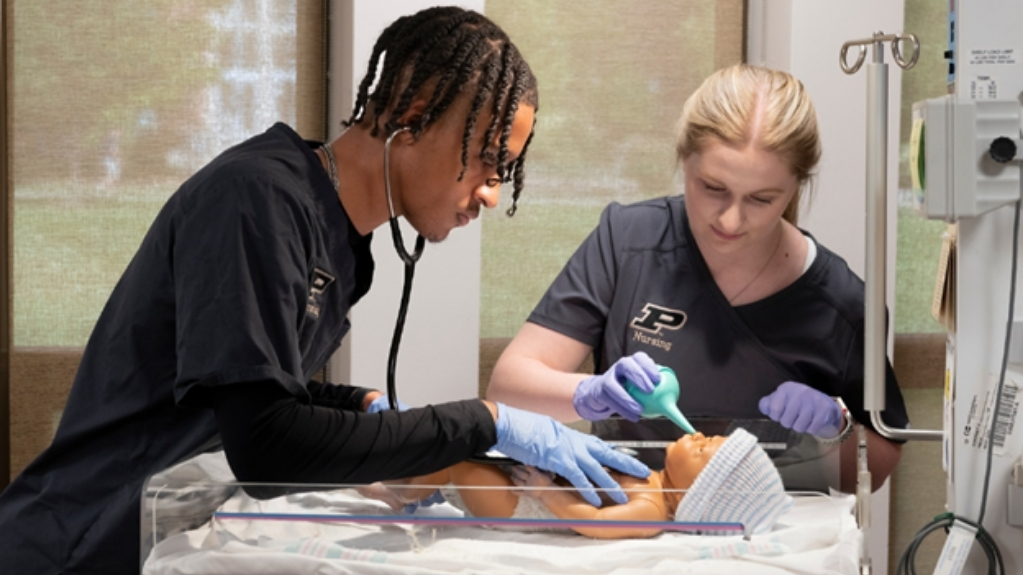 Nursing students practice newborn care using a medical training mannequin.
