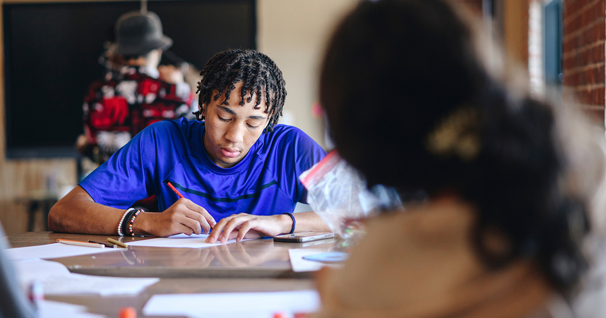student focusing on project at a table with another student