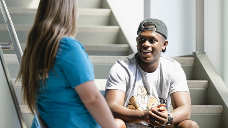 Students talking on indoor steps.