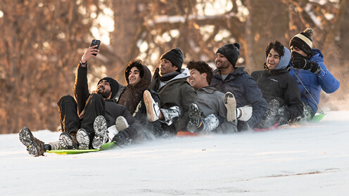 Group of students sledding downhill.