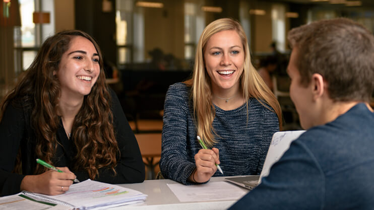 Students studying together at table in lobby.