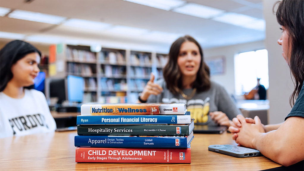 Students discuss family and consumer science topics with a stack of related books on the table
