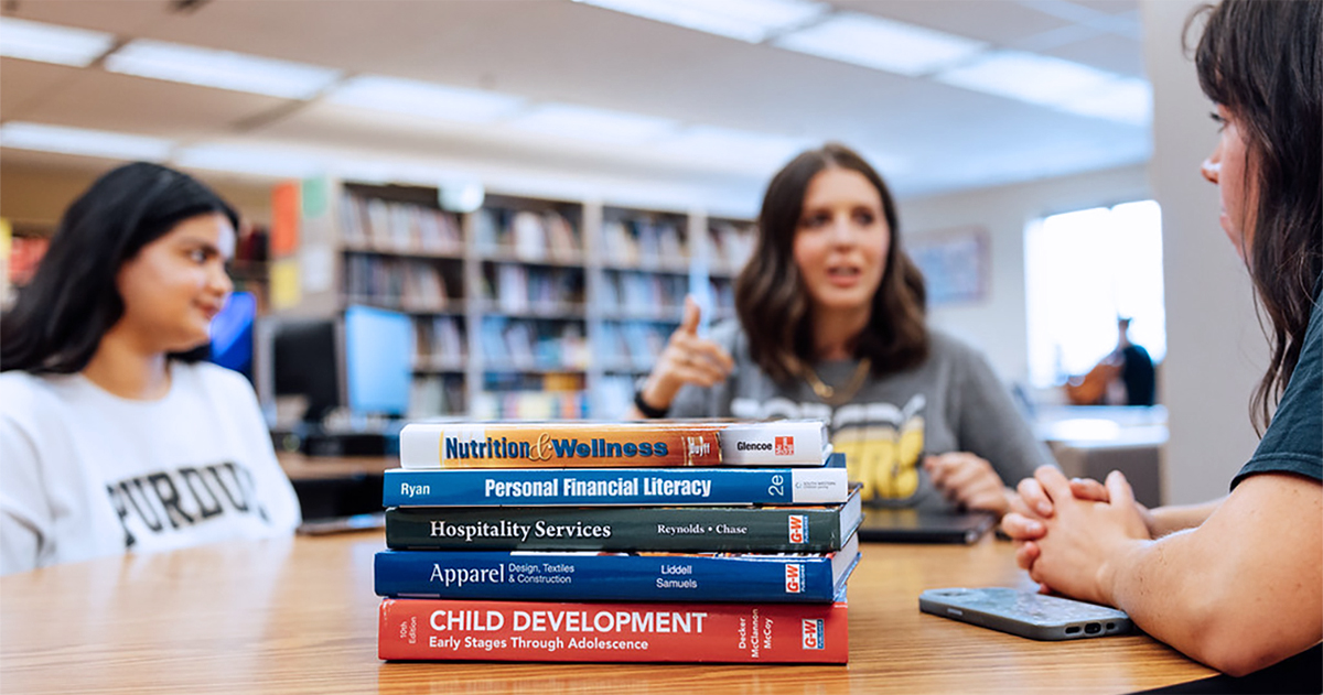 Students discuss family and consumer science topics with a stack of related books on the table