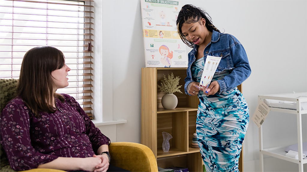 A student talks with an expecting mother in her nursery