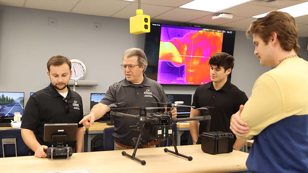 Students and a professor work on a drone