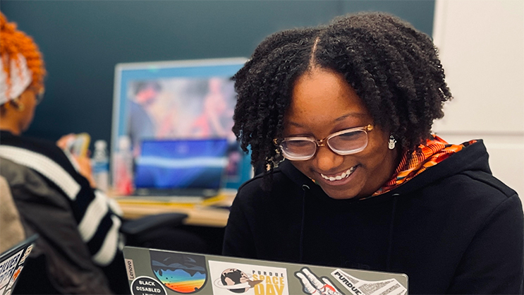 A student smiles as she works on her laptop.