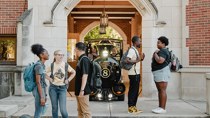 Students gathered outside of Cary Quadrangle Residence Hall with Boilermaker Special train in the background
