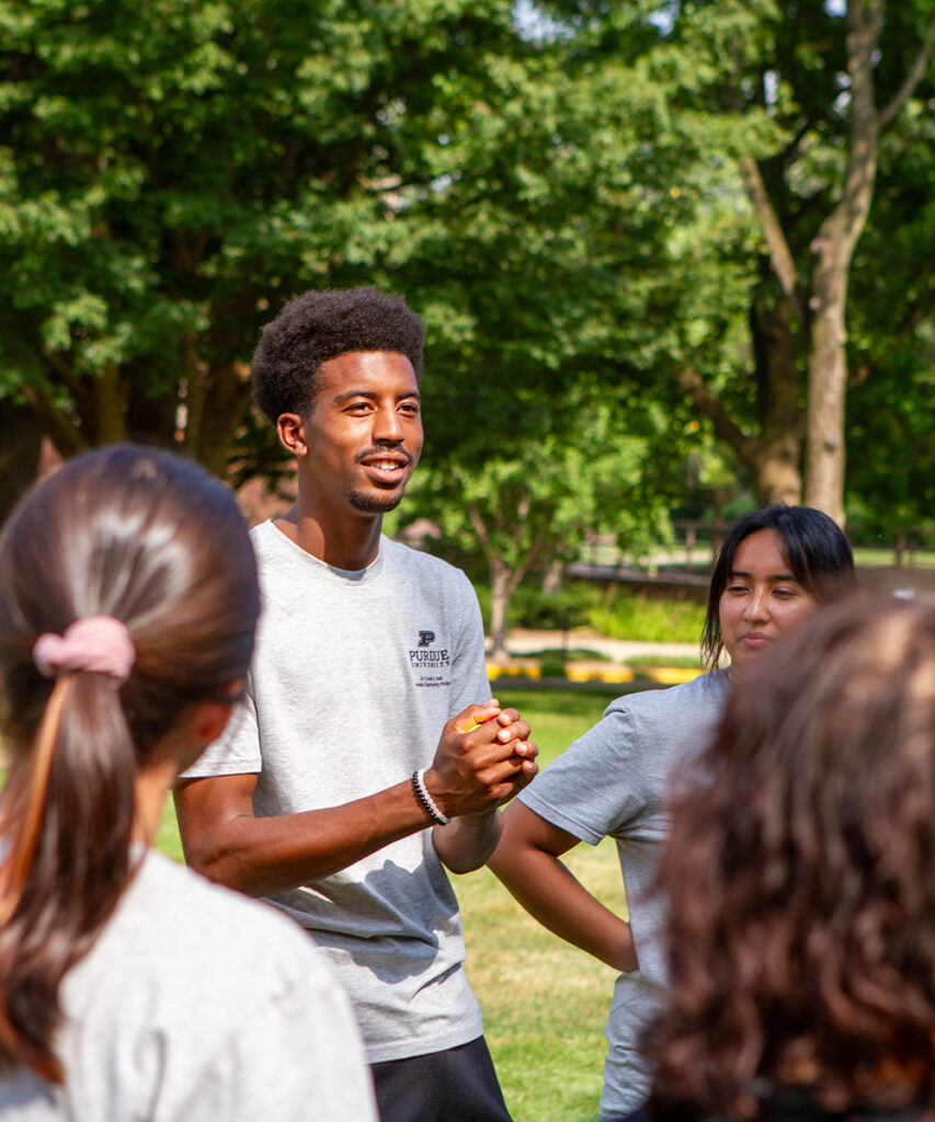 A student leads a group activity outside on a summer day